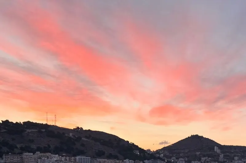 Pink and coral clouds over the hills of Sarandë at sunset