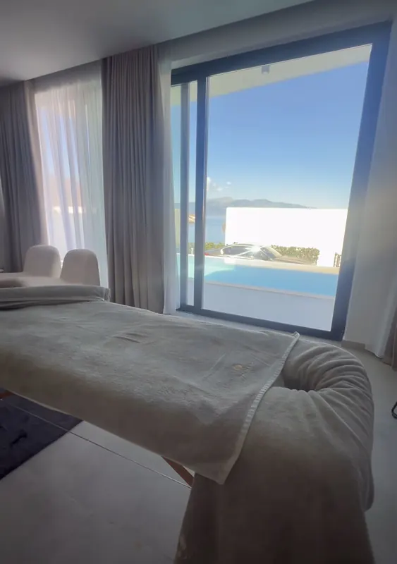 Massage bed in a villa room with a pool and the sea beyond the window