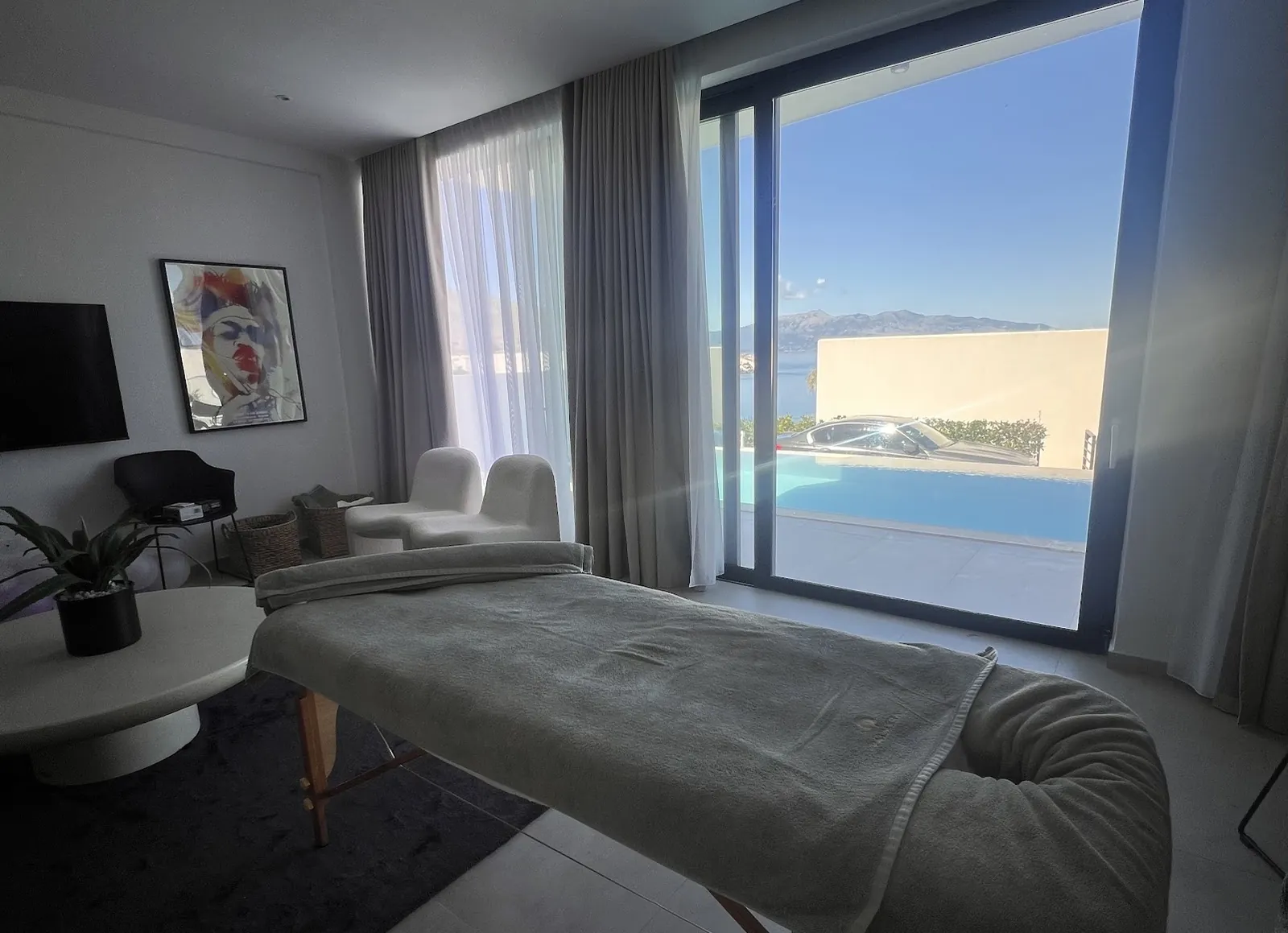Villa living room with a massage bed beside a window onto the pool and the sea