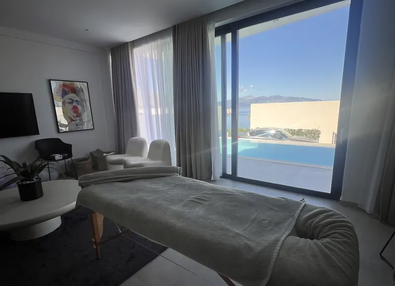 Villa room with a massage bed and a pool outside